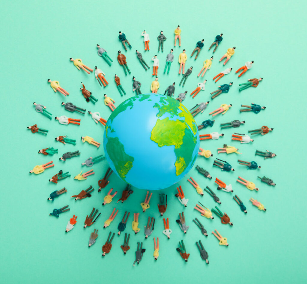 Miniature People Around Earth Model on Green Surface