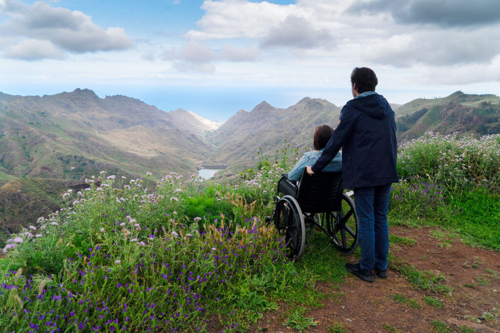 young man and woman in a wheelchair looking out over a clif